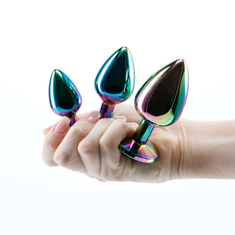A hand holding three plugs from the Rear Assets Rainbow Gem Trainer Kit.