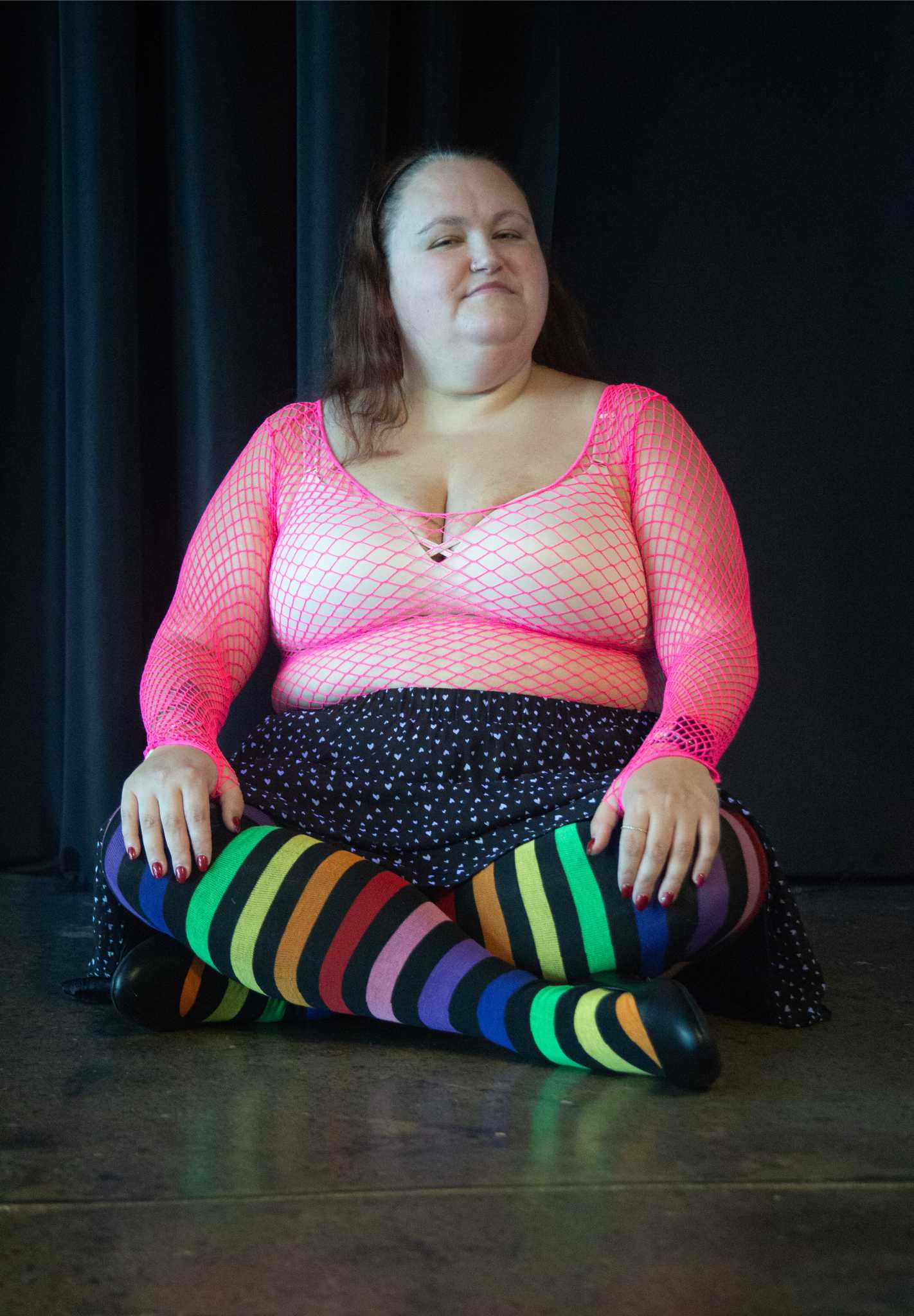 plus size model wearing Aurora Rainbow Over the Knee Rainbow Socks sitting criss cross applesauce