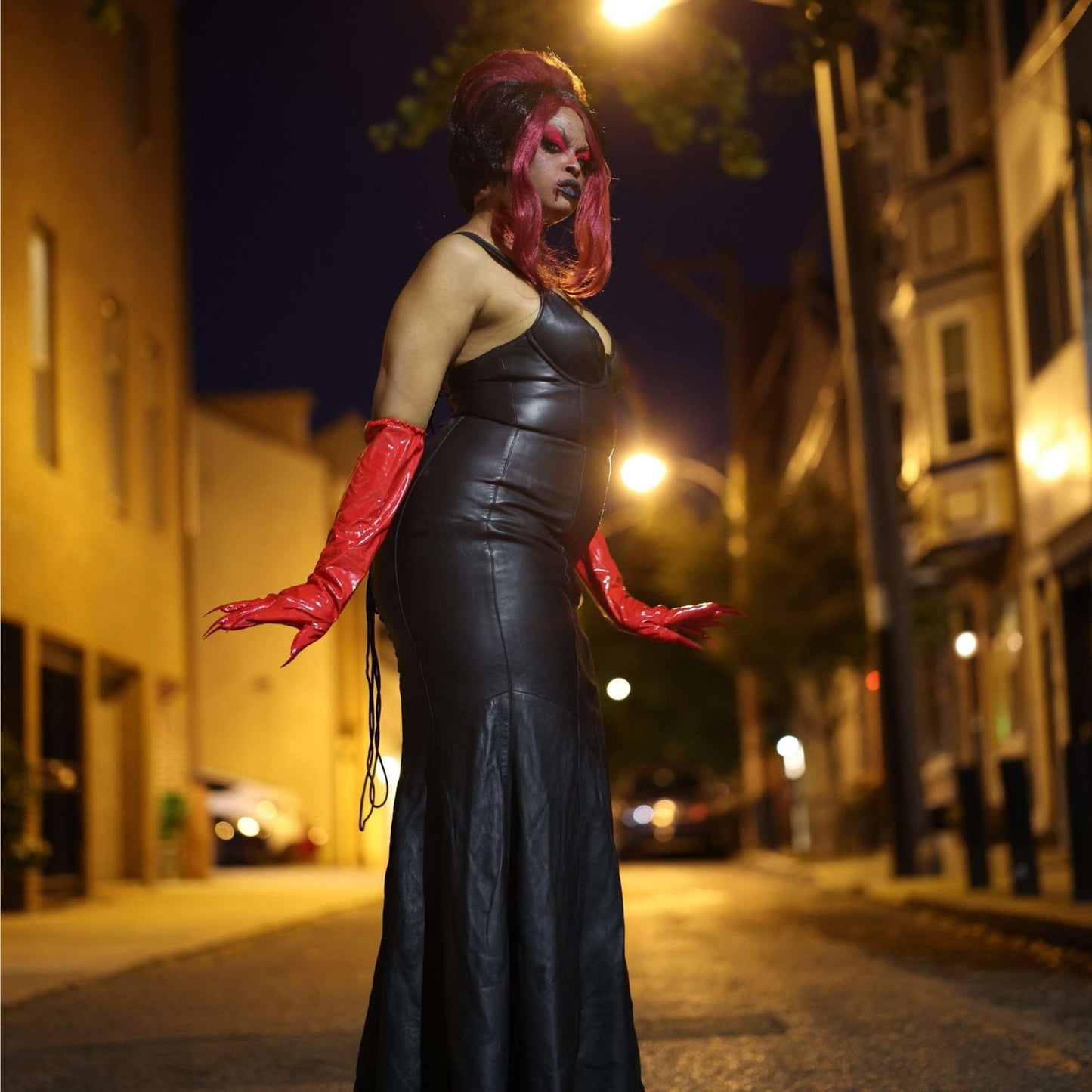 Model wearing red long stretch vinyl claw gloves and black leather dress