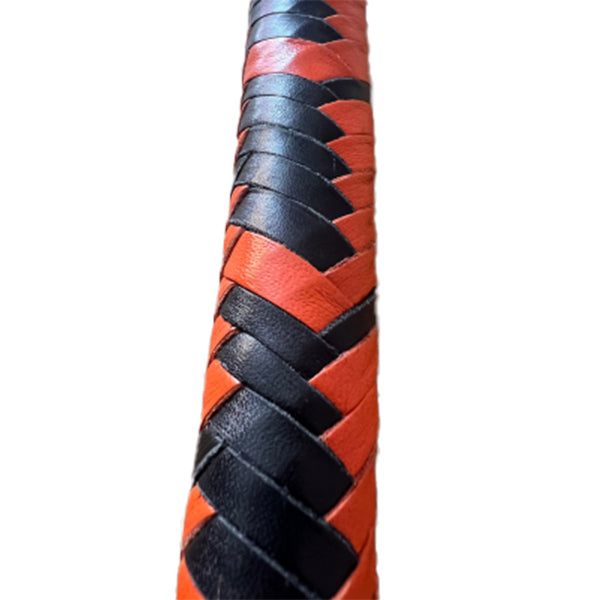 A close up of the body of orange and black braided single tail whip.