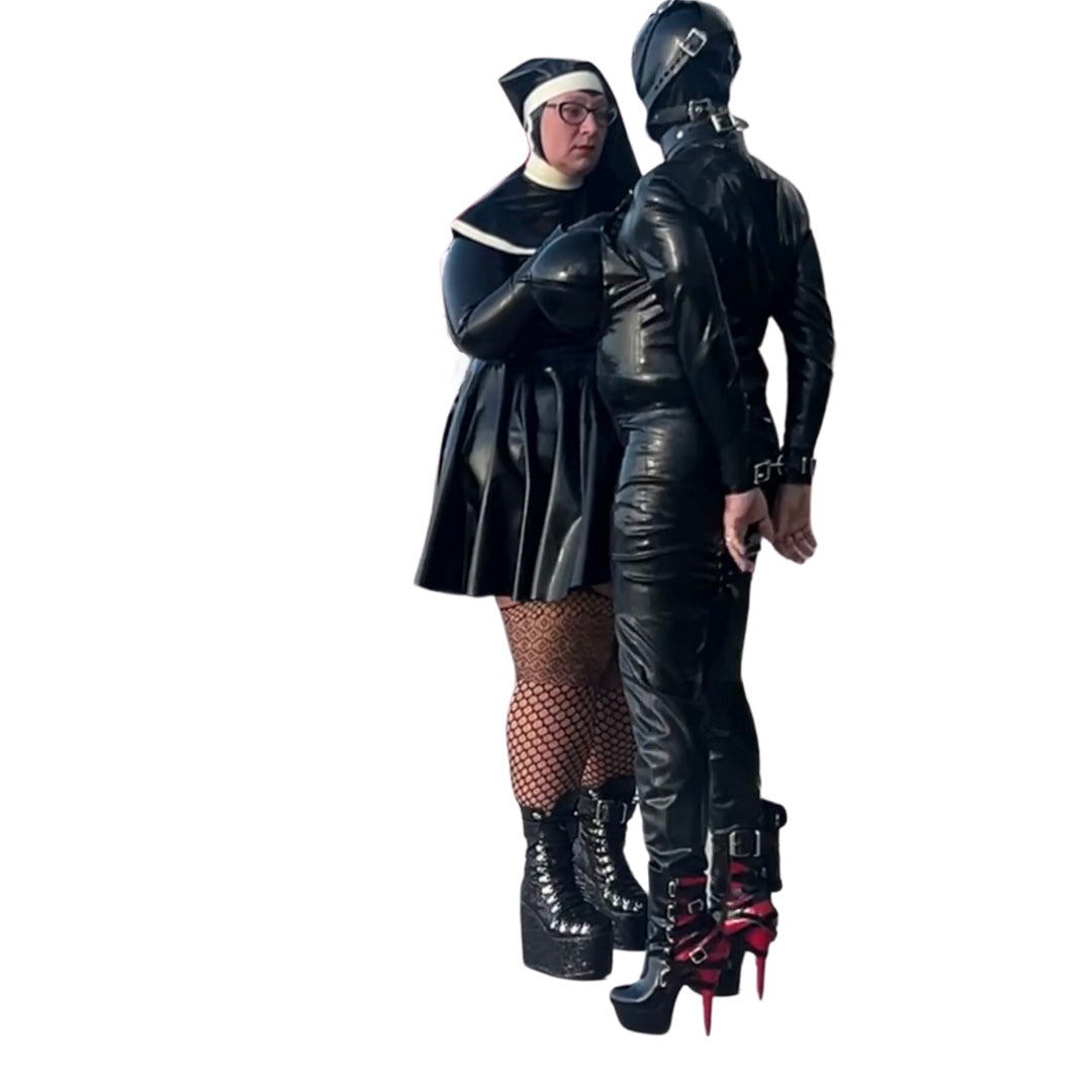 Model wearing Latex High-Neck Hepburn Dress, with Filthy Habbit  Headgear, with Drone model with wrist in restraints