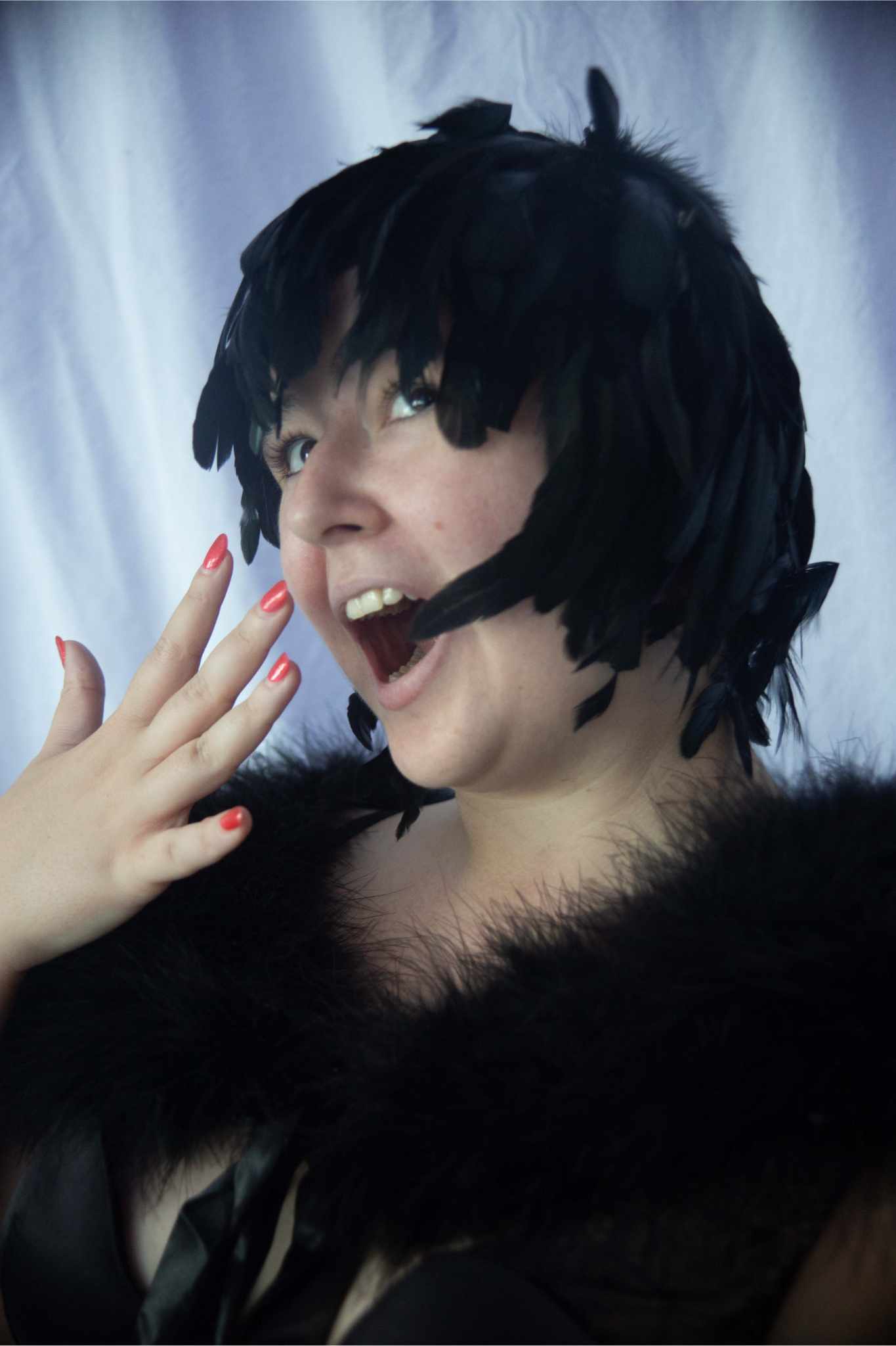 Model facing left with hand up wearing Schlappen Feather Wig