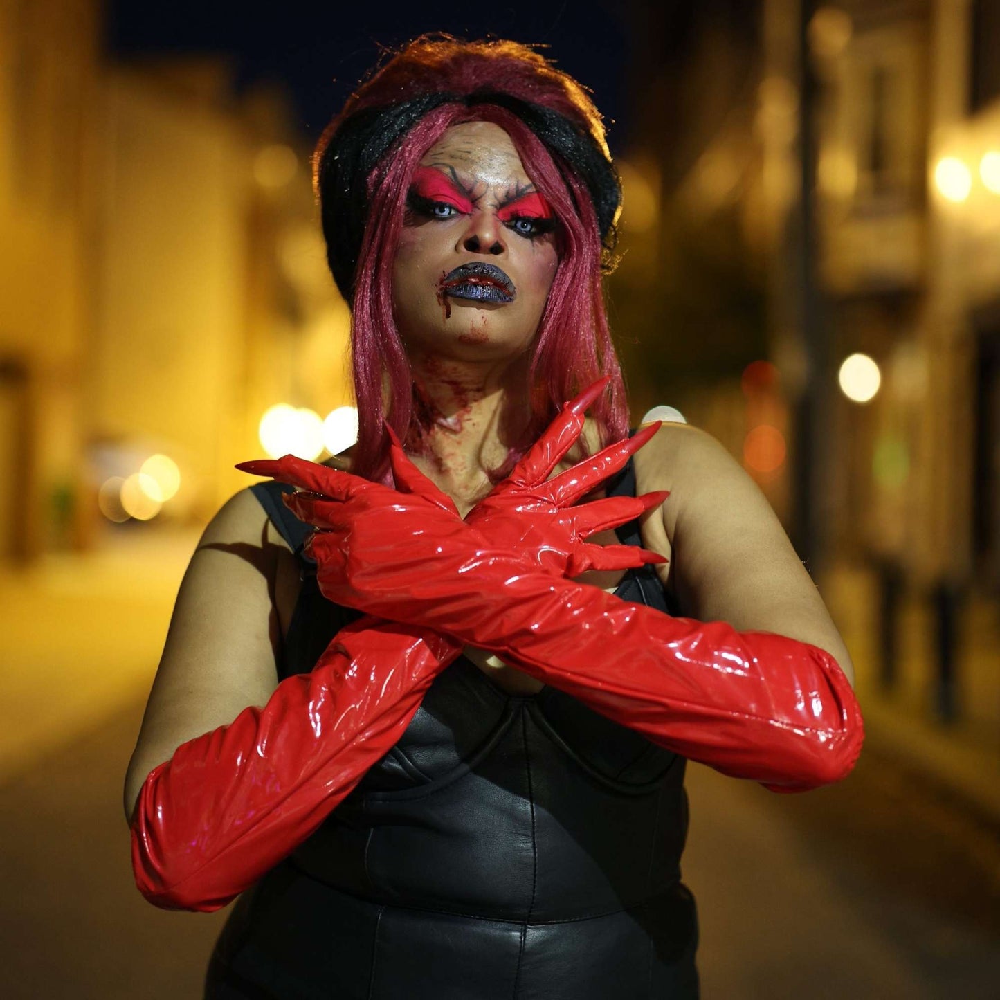 model wearing red Long Stretch Vinyl Claw Gloves with arms crossed against the chest