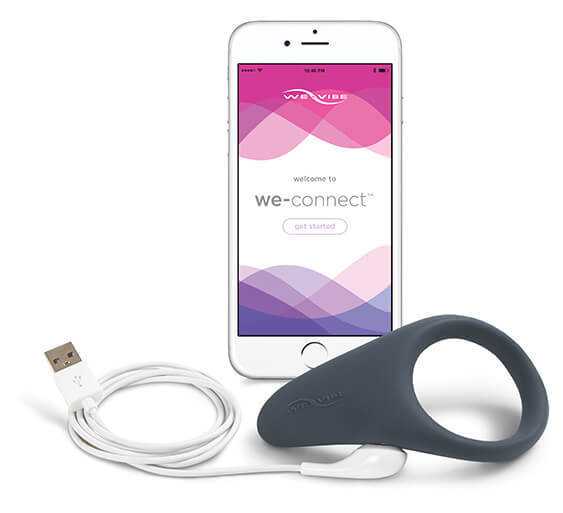 The The slate gray We-Vibe Verge Cock Ring and Perineum Vibrator with it's charging cable and a cell phone showing the We-Connect app.