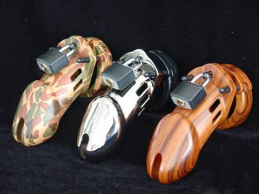 Three CB-6000 chastity belts. One, camouflage, one silver and one wooden.