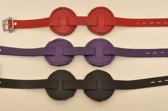One red, one purple and one black round blindfold lying parallel to each other.