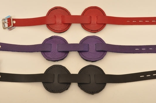One red, one purple and one black round blindfold lying parallel to each other.