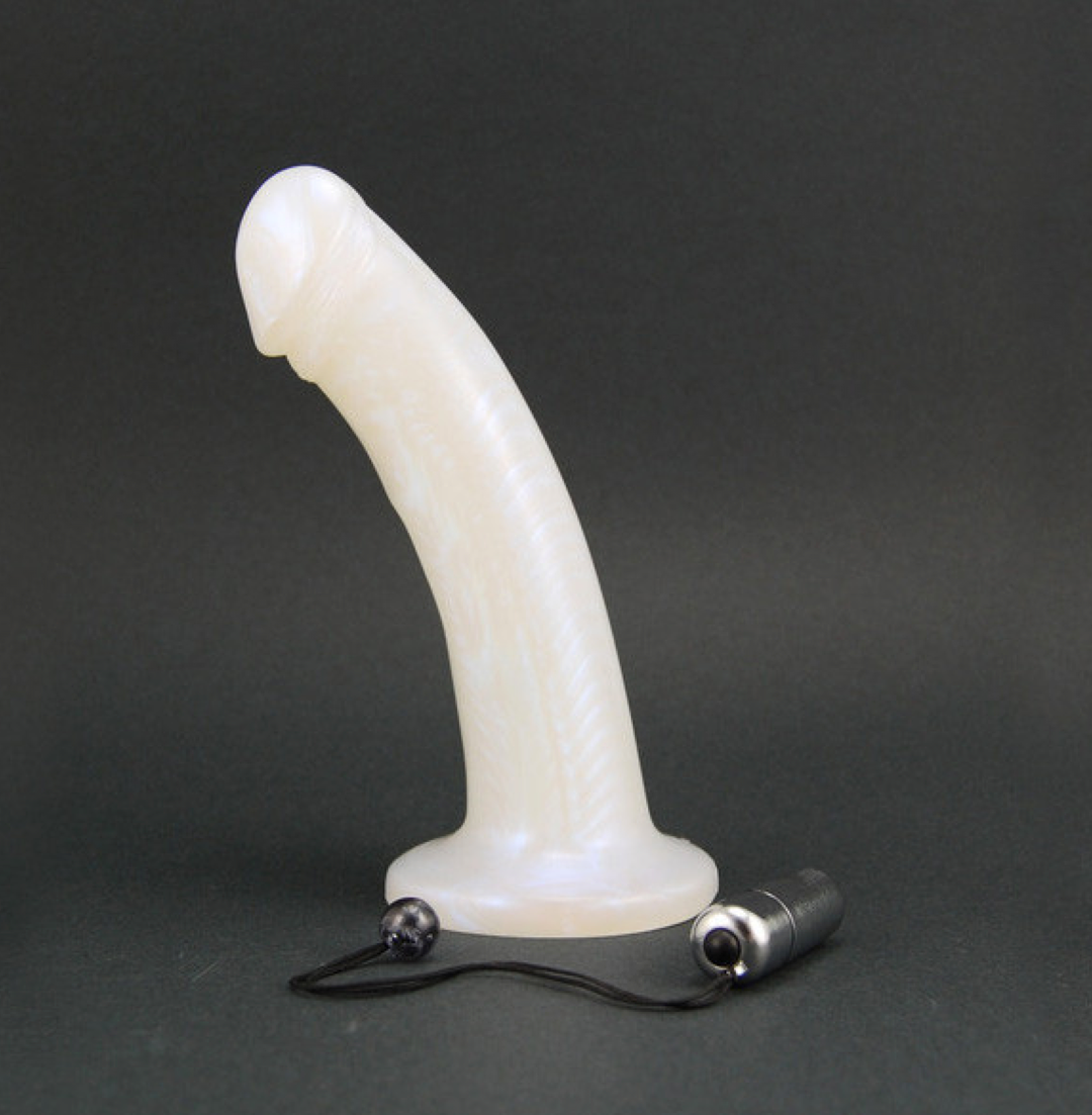 Ivory Pearl leo vibrating dildo standing up with silver bullet with cord in front of it