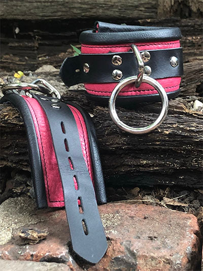 Pink rolled leather deluxe cuffs, one closed other laid out to show length.