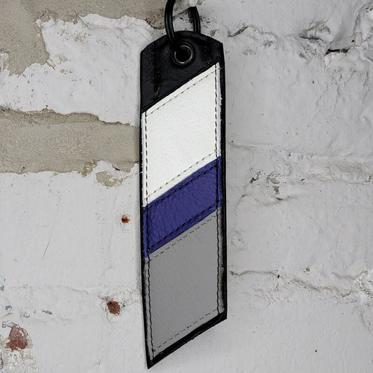 Demisexual pride flag key ring against a wall