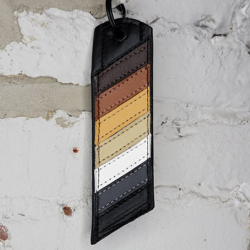 Bear pride flag key ring against a wall