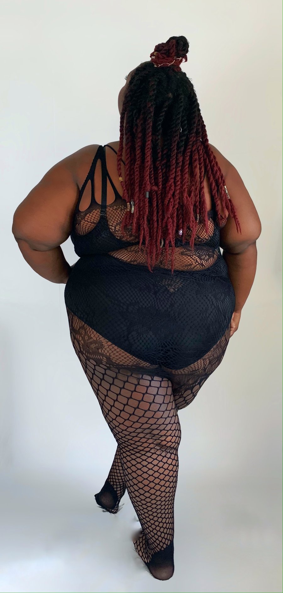 Plus size model wearing black Kixies All-in-One Bodystocking One Size XS-5XL, rear view.