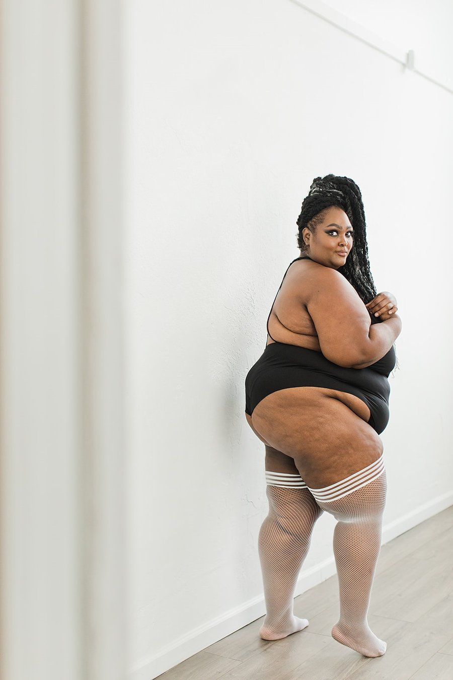 Plus size Sammy White Fishnet Thigh Highs on standing model. left side view.