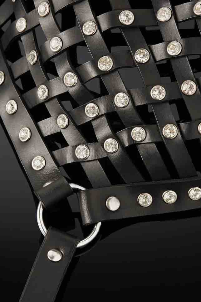 A closeup of an O-ring, rivets and straps of the Opulanta Obscura Luxury Leather Strapped Mask.