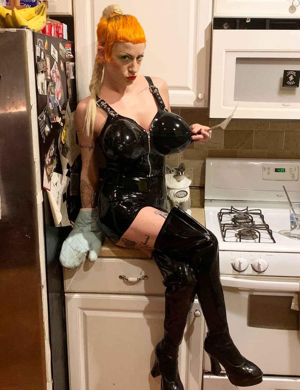 A model wearing the DeMask Inflatable Torpedo Tatas Top with a matching skirt and thigh high boots.