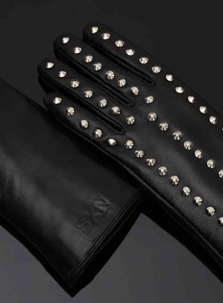 The outside of the Spiked Leather Forearm Glove lying flat on a black surface.