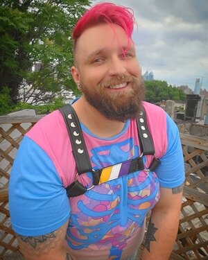 A model showing the front of a harness with the Non-Binary Pride Flag Center Strap.