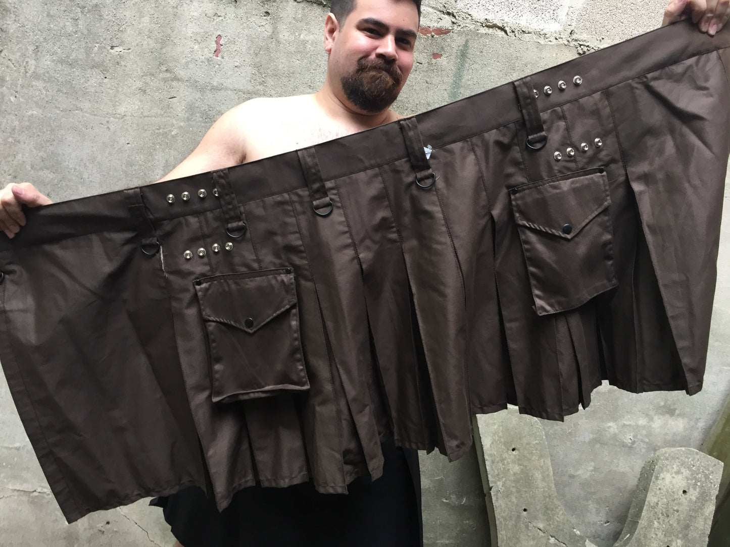 Model holding up the brown Cargo Kilt.