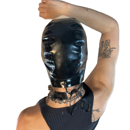 A model wearing black open mouth and eye basic latex hood, rear view.