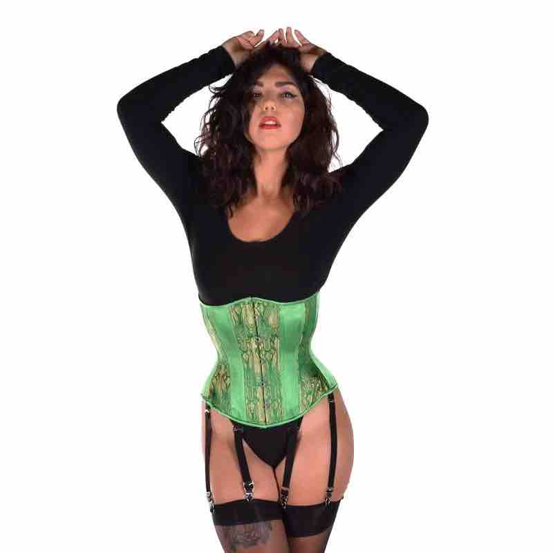 A model wearing the Emerald & Gold Brocade Hourglass Cincher over a black leotard with thigh high stockings attached to garters.