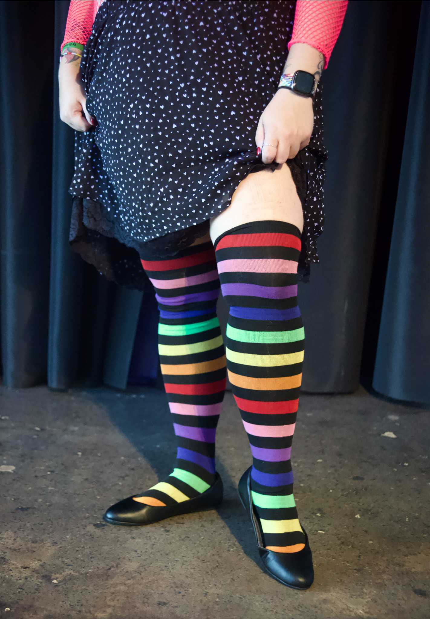 Plus size model wearing Rainbow Over the Knee Rainbow Socks with the leg extended