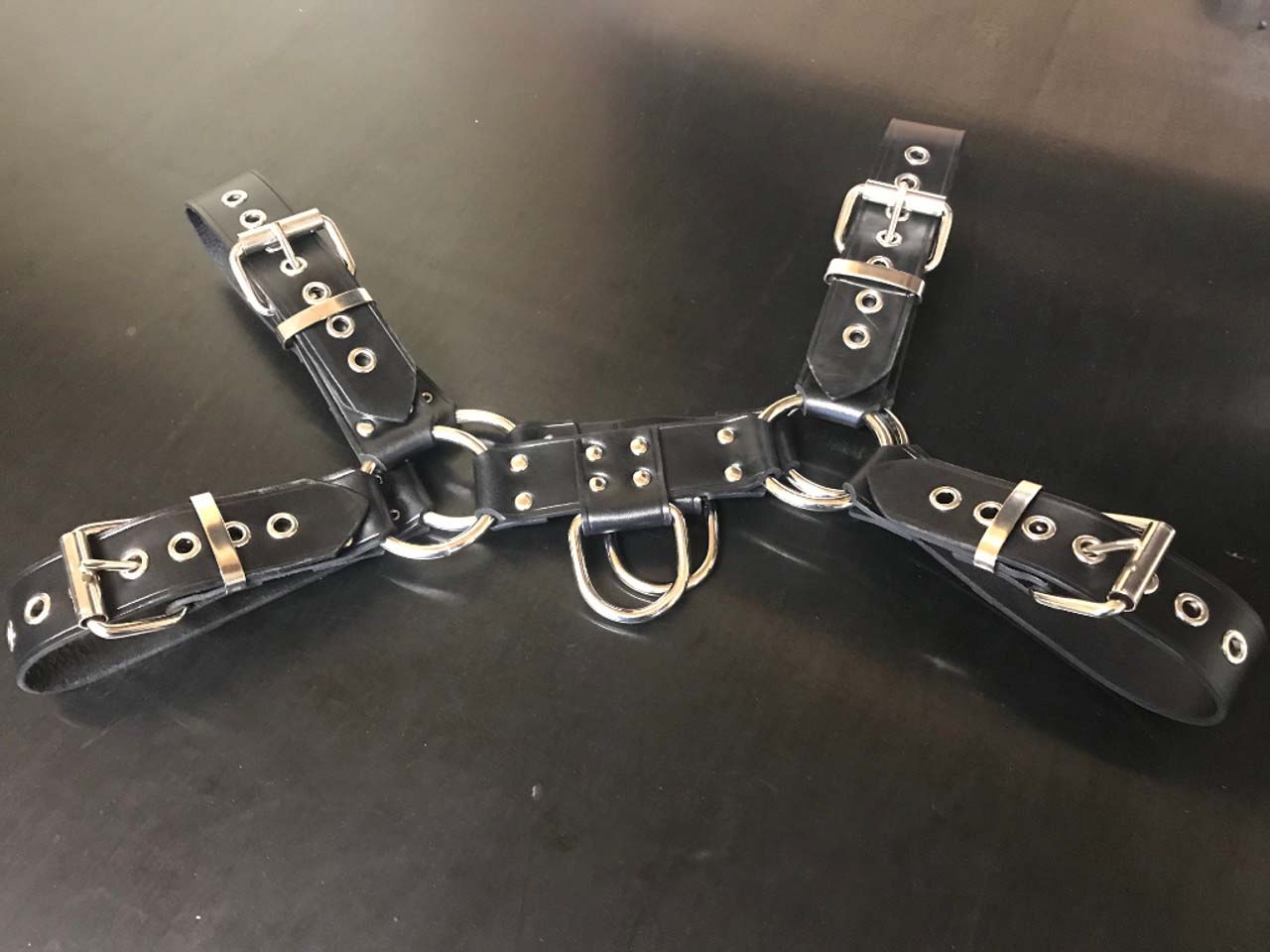 The Leather Bulldog Harness with D-Ring laying flat, front view.