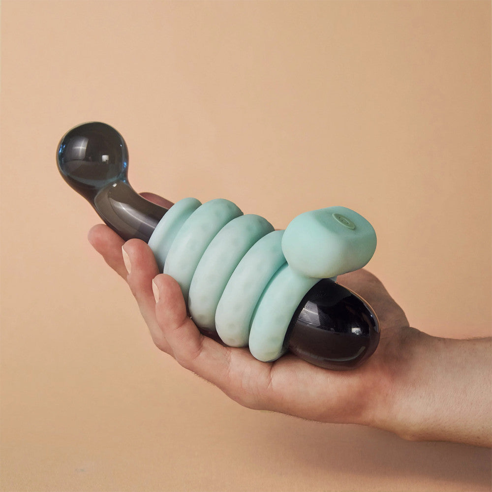 A hand holding a dildo wearing the classic Jade OhNut Vibrating ring and its buffers.