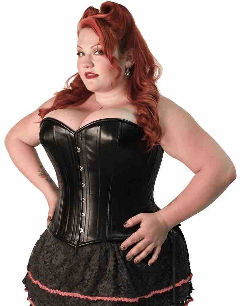 A plus size model wearing the Black Leather Short Overbust Corset -Slim over a black lace skirt.