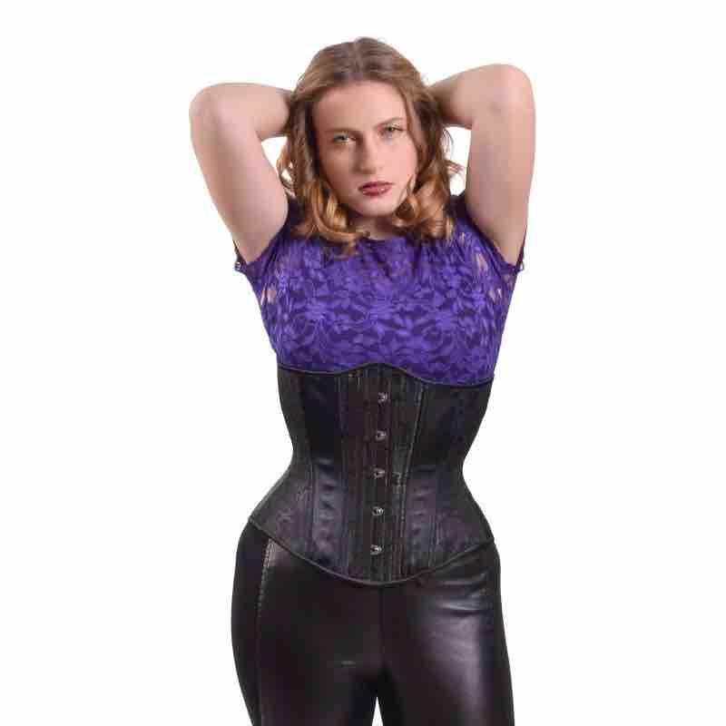 A model wearing the Black Rose Brocade Mid-Length Underbust Corset - Hourglass over a purple lace shirt and black pants.