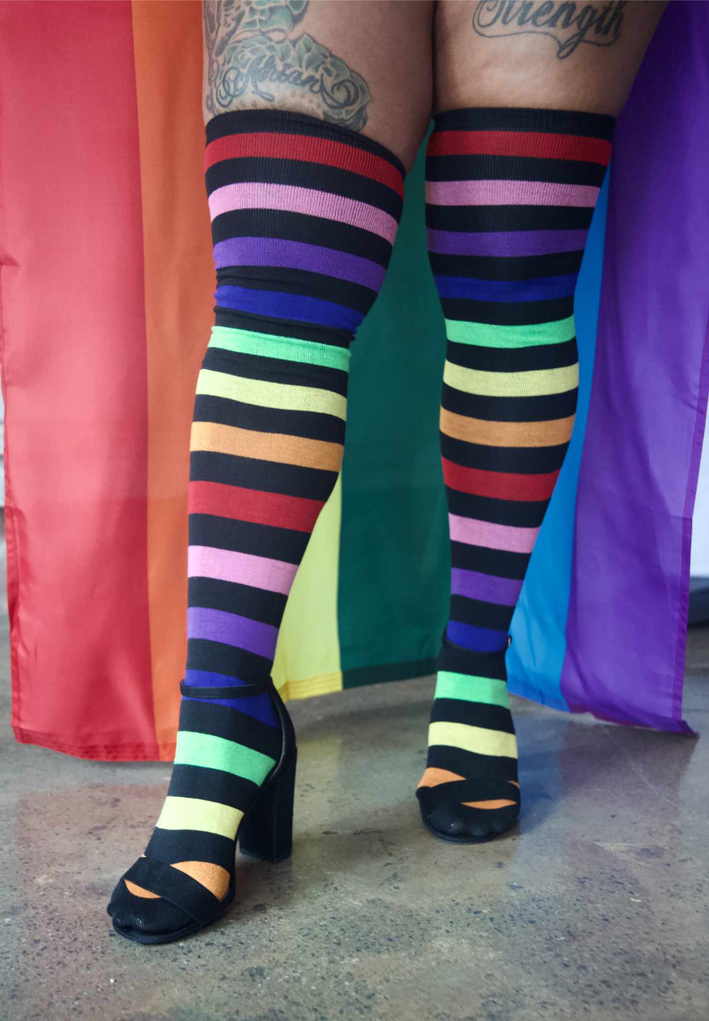 model wearing Aurora Rainbow Over the Knee Rainbow Socks with right leg extended