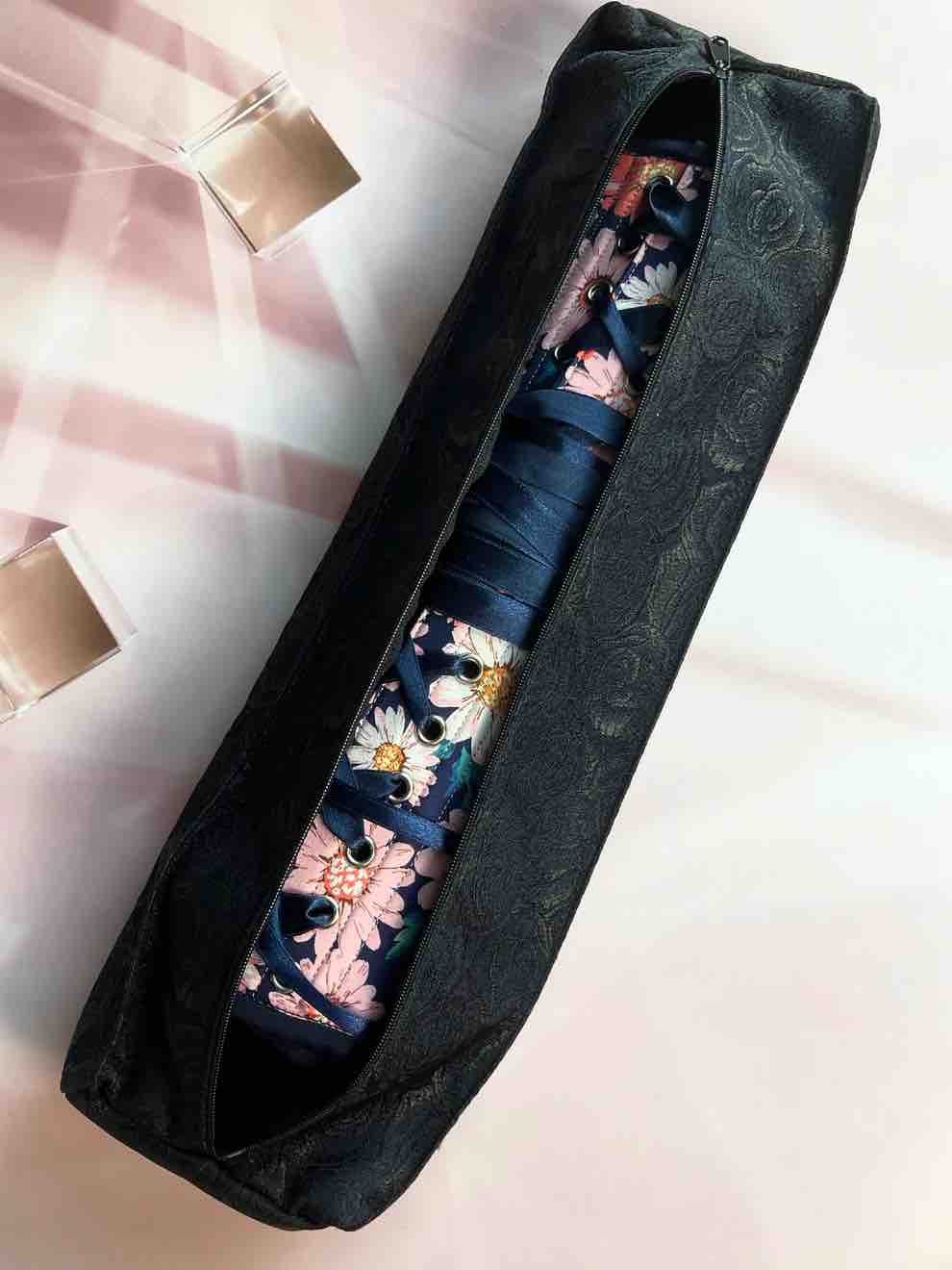 A corset with a flower pattern inside the black brocade Underbust Corset Bag with zipper open.