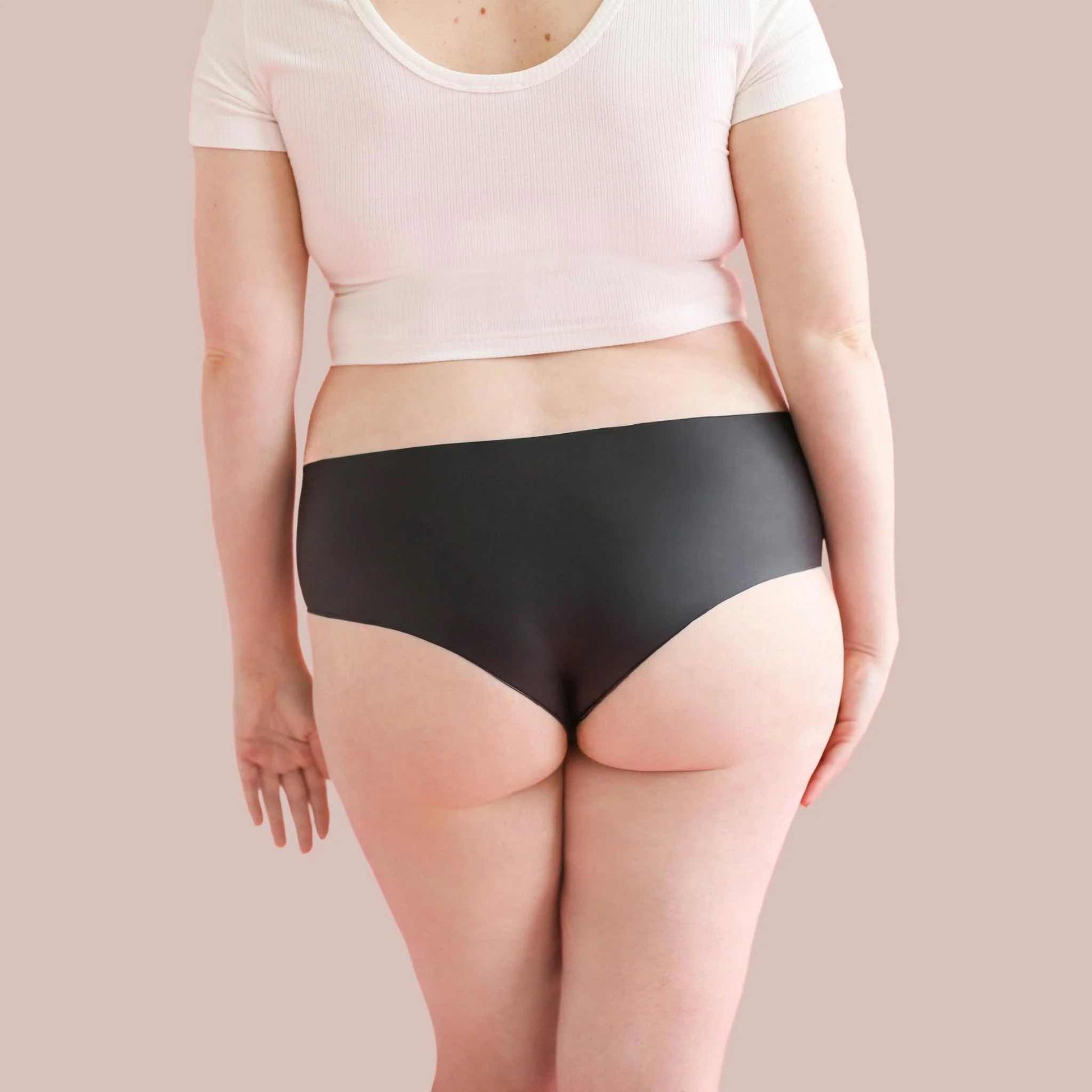 A plus sized model wearing the opaque black shortie Lorals Panties For Pleasure and Comfort, rear view.