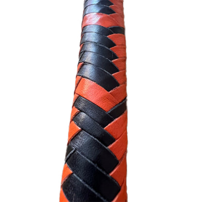 A close up of the body of orange and black braided single tail whip.