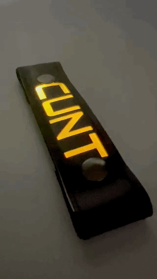 A Gif of the "CUNT" Glow Center Strap flashing in different colors.