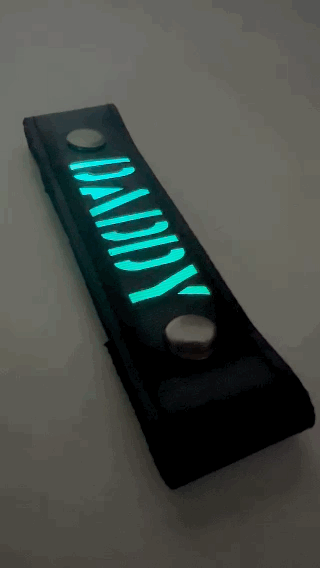 A Gif of the "DADDY" Glow Center Strap flashing in different colors.