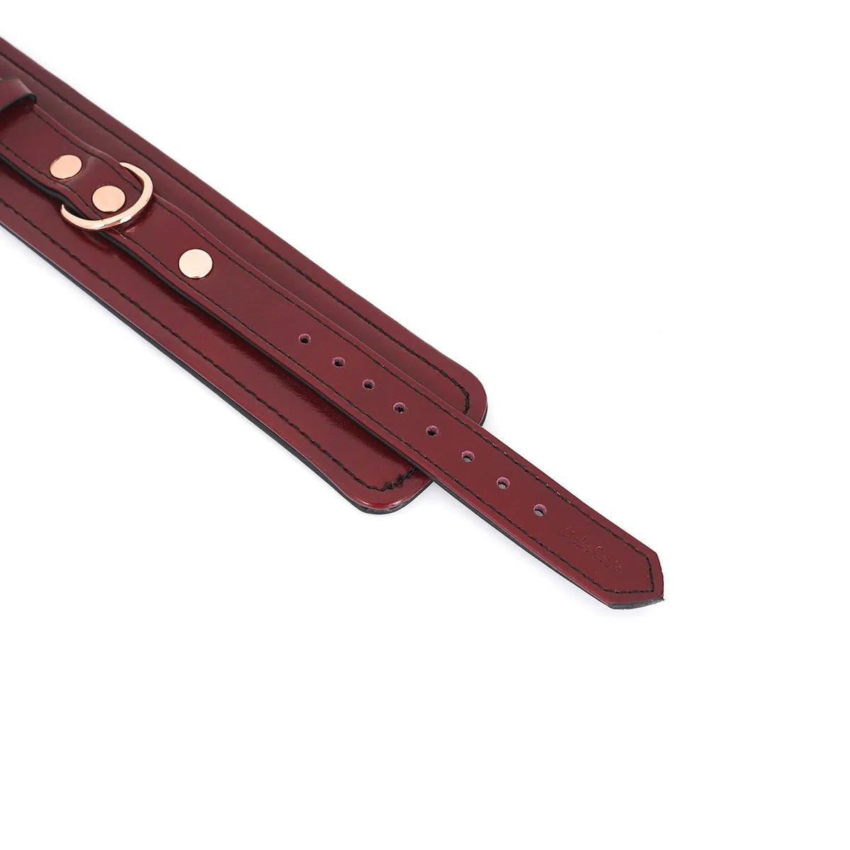 A close up of the strap end of the Burgundy Leather Cuffs with Rose Gold Hardware.
