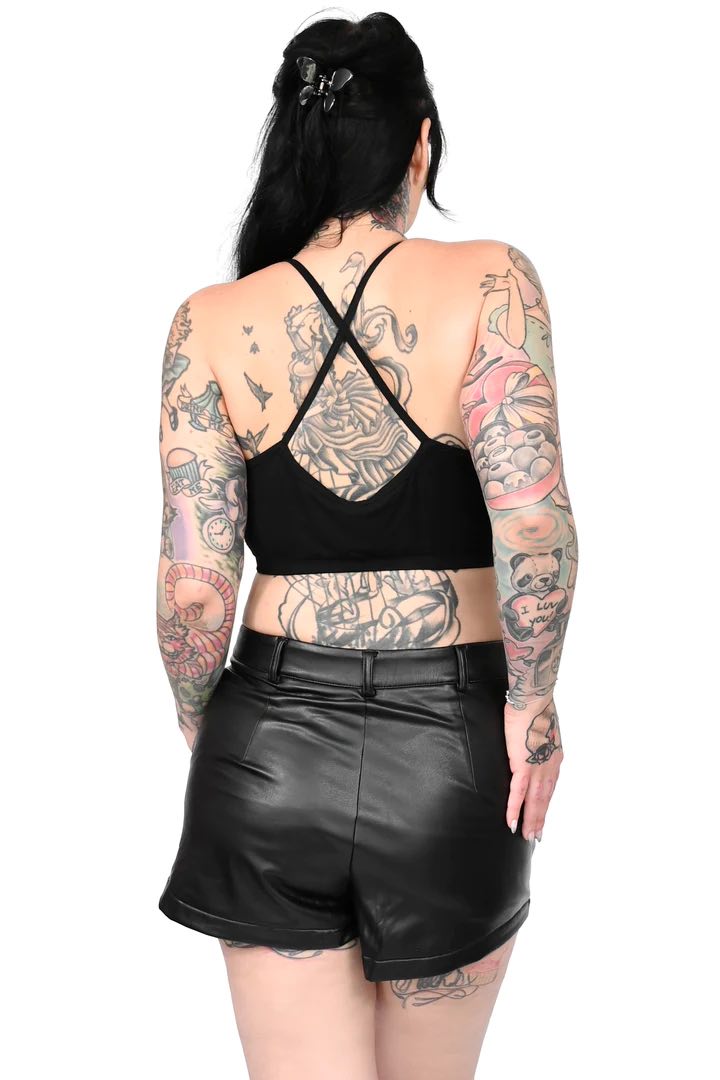 A heavily tattooed model wearing a black halter top with the Faux Leather Shorts, rear view.