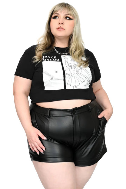 A plus size model wearing a black and white t-shirt with the Faux Leather Shorts, front view.