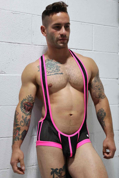 A model wearing the pink and black Dirty Boy Neon Trim Singlet against a white brick wall, front view.