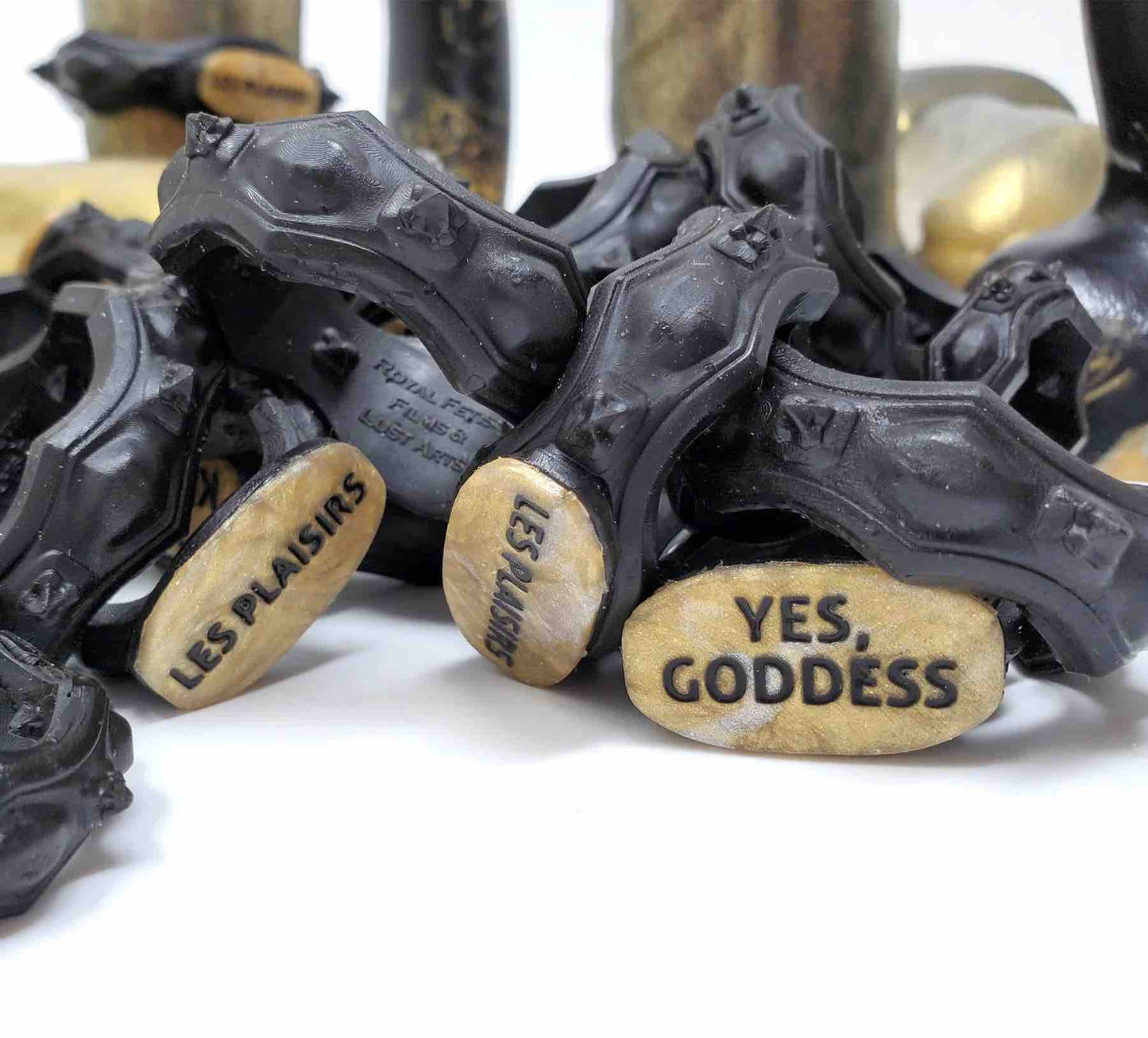 A pile of black and gold Royal Fetish FEMDOM Edging Body Bands.