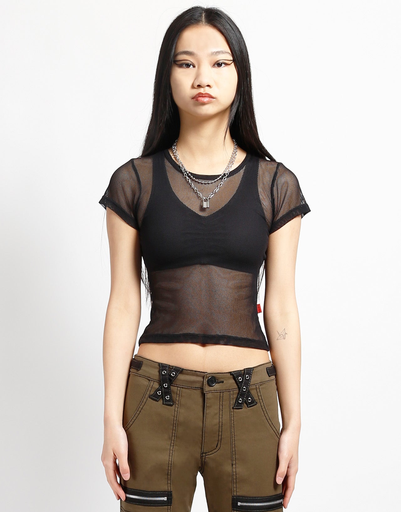 A model wearing the black Baby Short Sleeve Fishnet Tee Shirt with brown pants, front view.