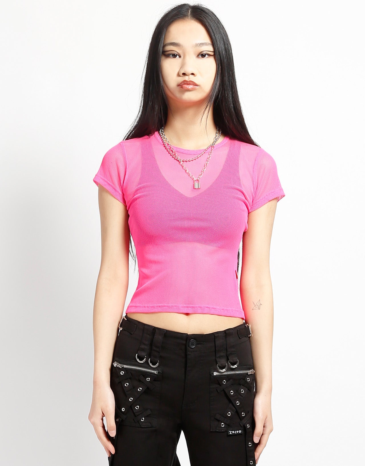A model wearing the pink Baby Short Sleeve Fishnet Tee Shirt with black pants, front view.