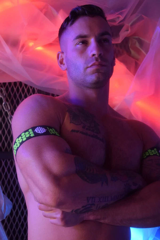 A model with arms folded wearing the neon green Hex Armband on both arms.