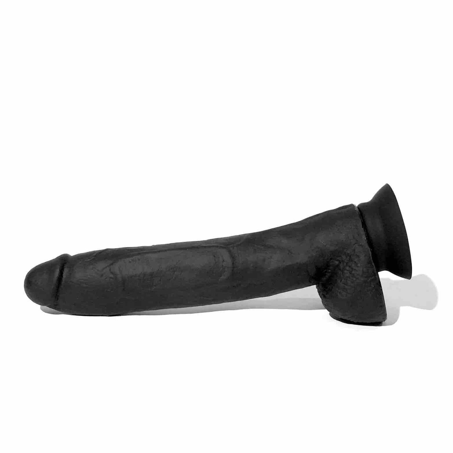 The 10 inch Boneyard Silicone Cock laying on its side with the suction cup attached.