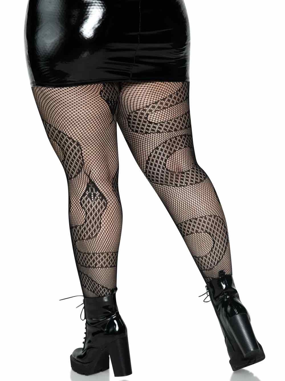A plus size model wearing the Snake Net Tights with black wetlook skirt and platform boots, rear view.