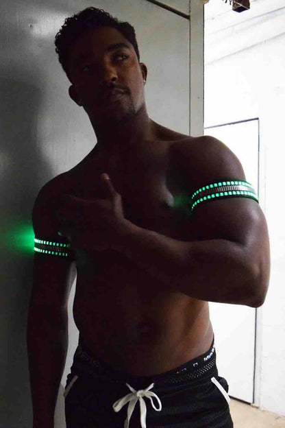 A model wearing the Mirror Light Armbands on both arms with green lights showing.