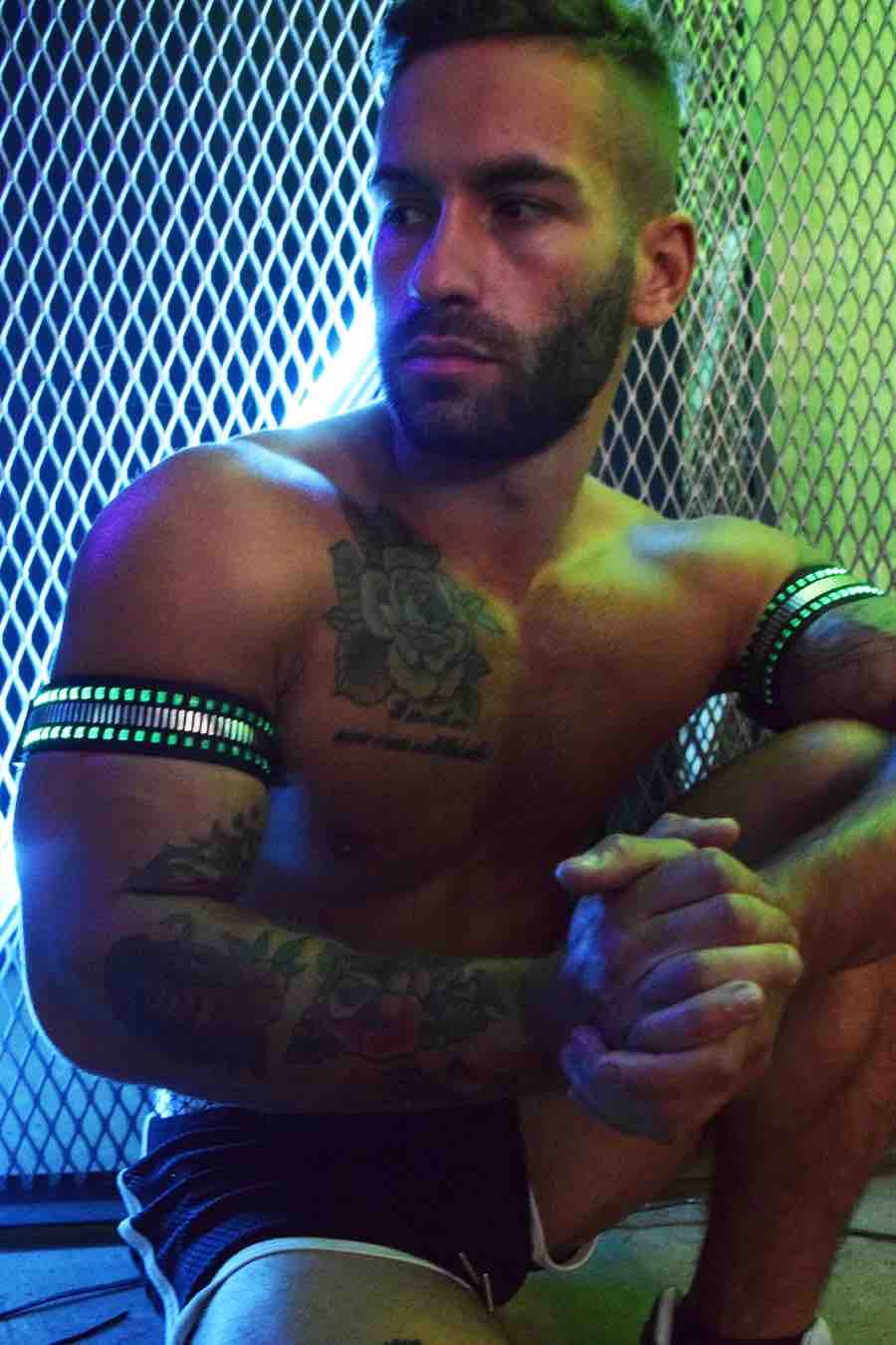 A model wearing the Mirror Light Armbands on both arms with green lights showing.