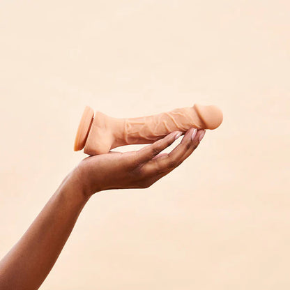 A hand holding the Vanilla dual density dildo.