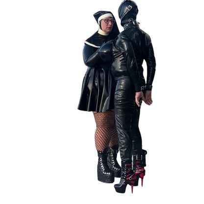 Model wearing Latex High-Neck Hepburn Dress, with Filthy Habbit  Headgear, with Drone model with wrist in restraints 