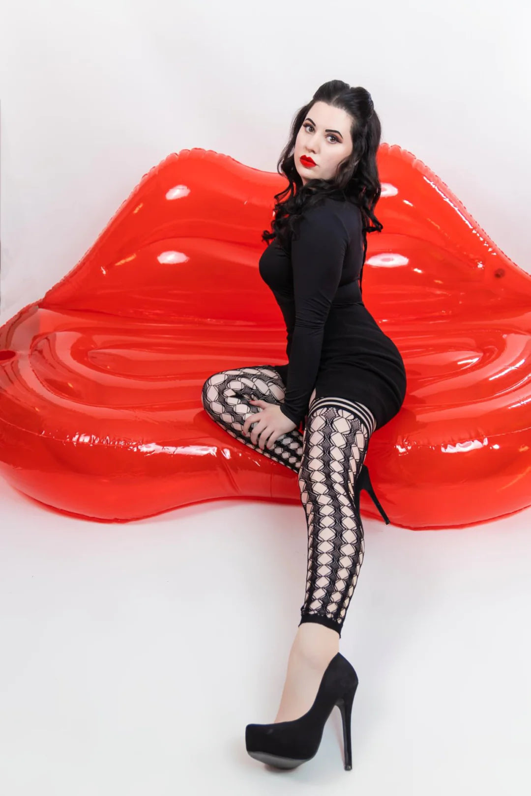 model sitting on inflatable red lip chair with leg extended wearing Jo Footless Thigh Highs